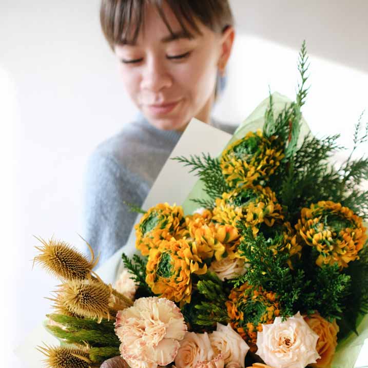 mujer sosteniendo flores en el interior que introduce alérgenos en el aire, lo cual es razón para elegir un purificador ir.